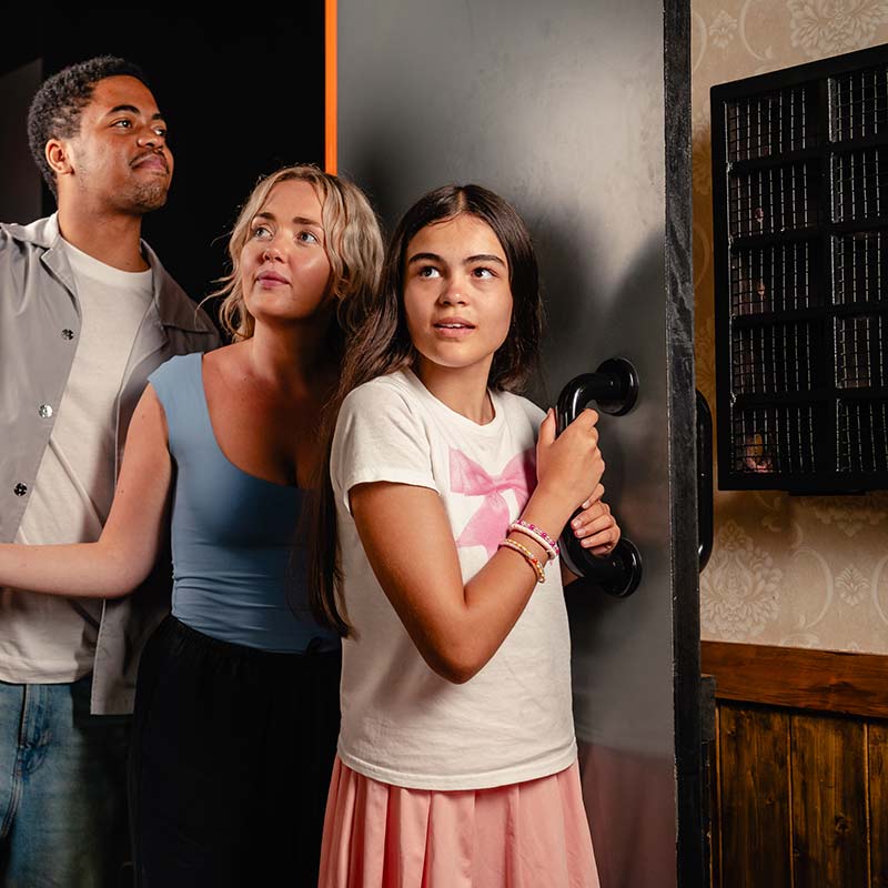 One man and two women entering an escape room